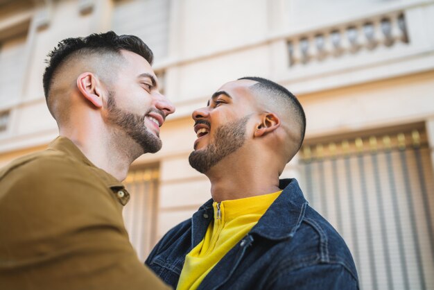 Retrato de feliz pareja gay pasar tiempo juntos y abrazarse en la calle.