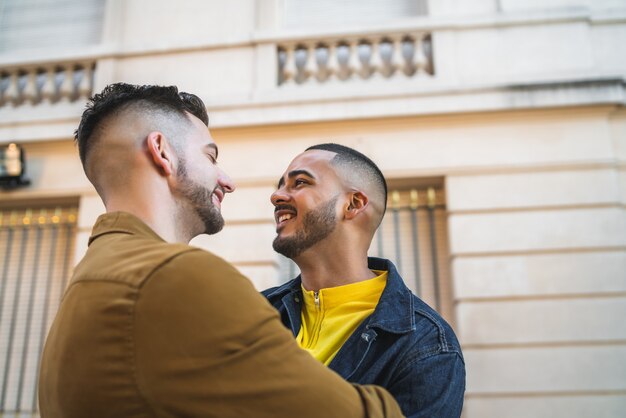 Retrato de feliz pareja gay pasar tiempo juntos y abrazarse en la calle
