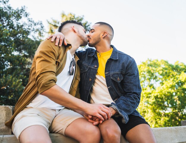 Retrato de feliz pareja gay pasar tiempo juntos y besarse en el parque. Concepto de amor y lgbt.