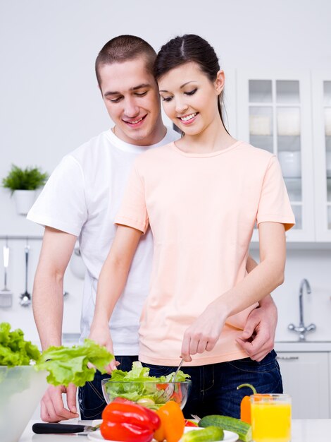 Retrato de la feliz pareja joven alegre haciendo el desayuno juntos