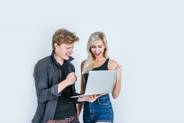 Retrato de la feliz pareja joven usando la computadora portátil