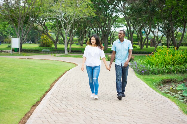 Retrato de la feliz pareja multiétnica caminando juntos en el parque.