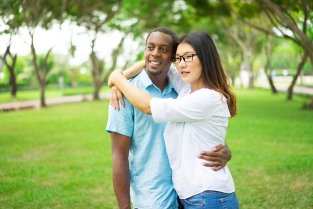 Retrato de feliz pareja multiétnica estudiante abrazando en el parque