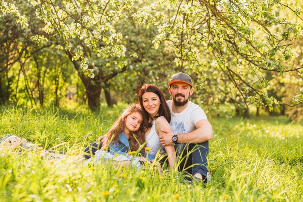 Retrato de la feliz pareja sentada en la hierba verde en el parque