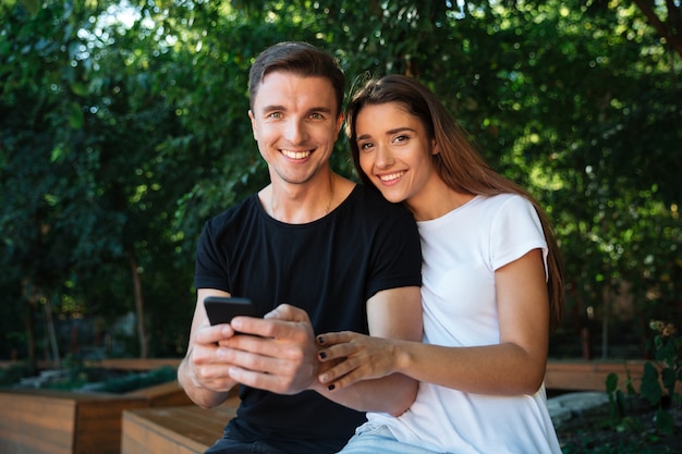 Retrato de una feliz pareja sonriente sosteniendo teléfono móvil