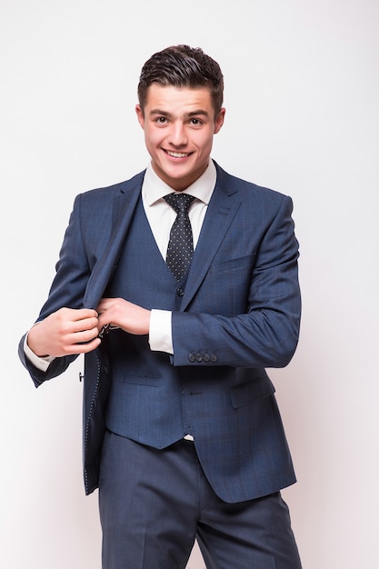 Retrato de feliz sonriente joven empresario en traje azul aislado en la pared blanca