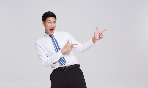 retrato de un feliz y sonriente joven y guapo hombre de negocios asiático señalando y mirando