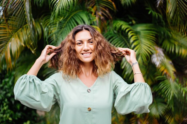 Retrato de feliz sonriente mujer bronceada europea con pelo corto y rizado en verano romántico vestido de manga larga fuera de villa