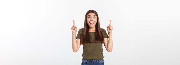 Retrato feliz y sorprendida señorita de pie aislada sobre fondo gris mirando la cámara pointi