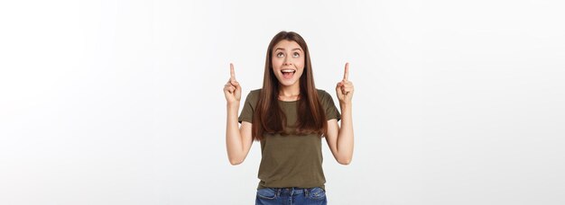 Retrato feliz y sorprendida señorita de pie aislada sobre fondo gris mirando la cámara pointi