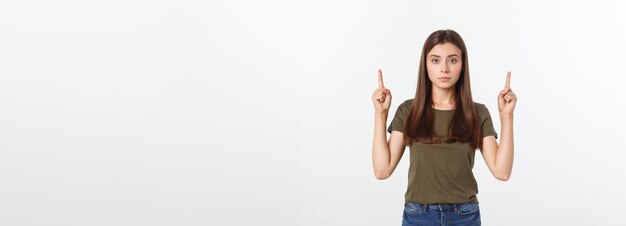 Retrato feliz y sorprendida señorita de pie aislada sobre fondo gris mirando la cámara pointi