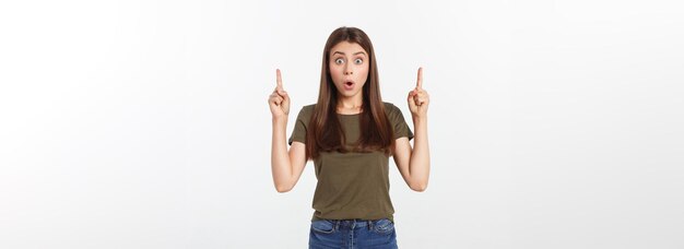 Retrato feliz y sorprendida señorita de pie aislada sobre fondo gris mirando la cámara pointi