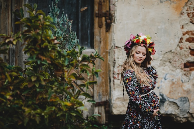 Retrato femenino Adorable mujer embarazada en poses de guirnalda de flores