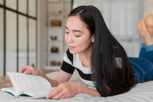 Retrato femenino en la cama leyendo