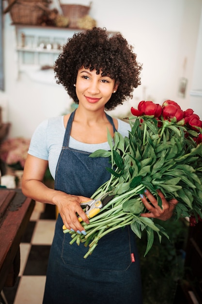 Foto gratuita retrato de una floristería femenina sonriente con ramo de flores rojas