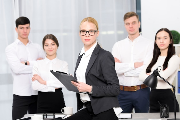 Retrato de una gerente femenina con portapapeles en la mano con su colega en el lugar de trabajo