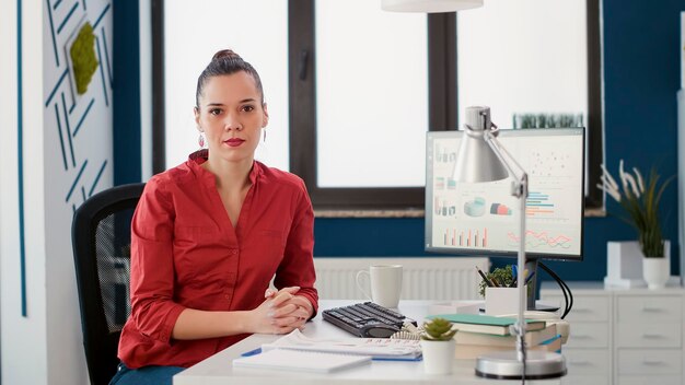 Retrato del gerente de proyecto sentado en el escritorio de la oficina para trabajar en el crecimiento del negocio con gráficos financieros y estadísticas de ventas. Consultor de marketing analizando diagramas de comercio electrónico en computadora.