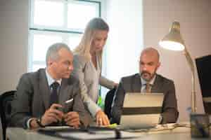 Foto gratuita retrato de gerentes discutiendo asuntos comerciales. dos hombres y mujeres confiados en el flujo de trabajo mirando la computadora con datos financieros, analizando el crecimiento de las ganancias. crecimiento empresarial, concepto de análisis financiero