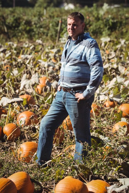 Retrato de granjero de pie en el campo de calabaza