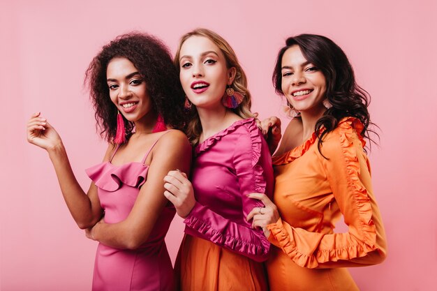 Retrato de un grupo de amigos sonriendo en la pared rosa