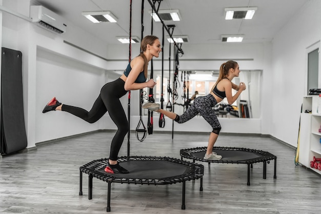 Retrato de un grupo de dos niñas en trampolines de gimnasia fitness en el gimnasio