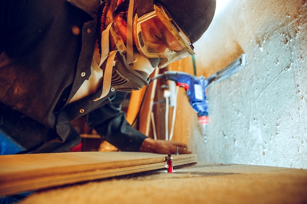 Retrato de guapo carpintero trabajando con patines de madera en el taller