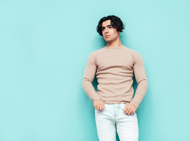 Retrato de guapo confiado con estilo hipster lambersexual modelo Hombre vestido con ropa de verano Moda hombre aislado en estudio Posando cerca de la pared azul