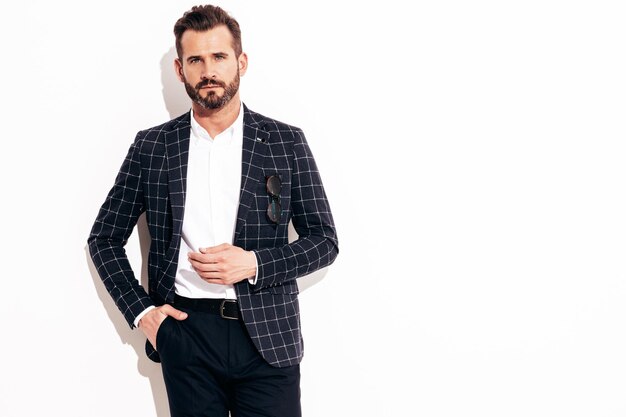 Retrato de guapo modelo lambersexual con estilo inconformista confiado Hombre moderno sexy vestido con traje negro elegante Hombre de moda posando en el estudio cerca de la pared blanca