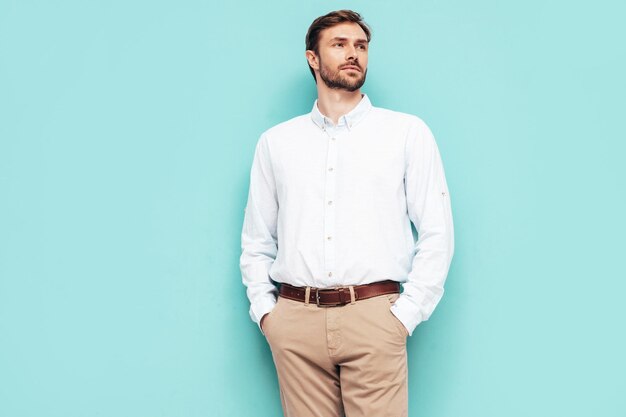 Retrato de guapo modelo sonriente Hombre elegante sexy vestido con camisa y pantalón Hombre hipster de moda posando junto a la pared azul en el estudio Aislado