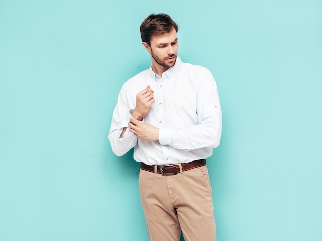 Retrato de guapo modelo sonriente Hombre elegante sexy vestido con camisa y pantalón Hombre hipster de moda posando junto a la pared azul en el estudio Aislado