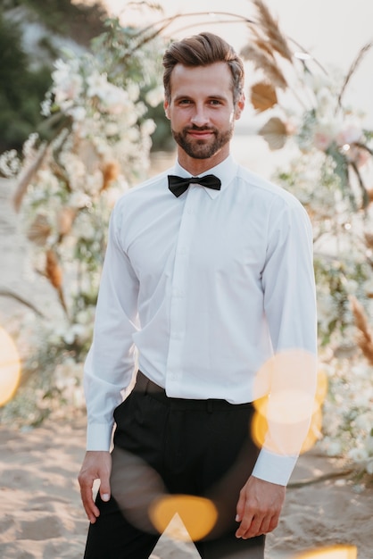 Foto gratuita retrato de guapo novio en su boda en la playa