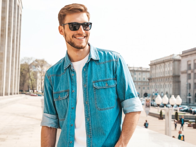 Retrato de guapo sonriente elegante hipster lumbersexual empresario modelo. Hombre vestido con ropa de chaqueta de jeans.