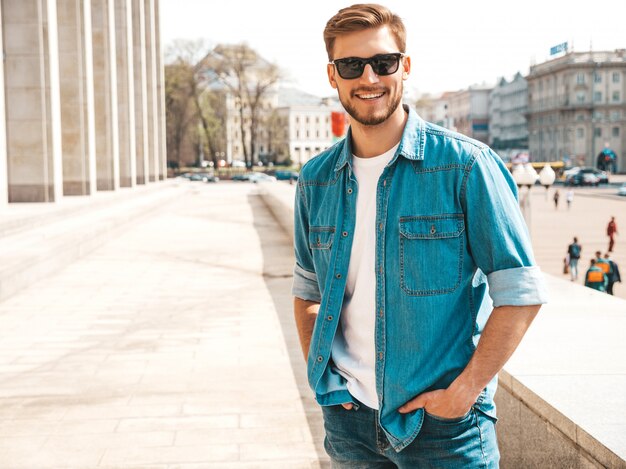 Retrato de guapo sonriente elegante hipster lumbersexual empresario modelo. Hombre vestido con ropa de chaqueta de jeans.