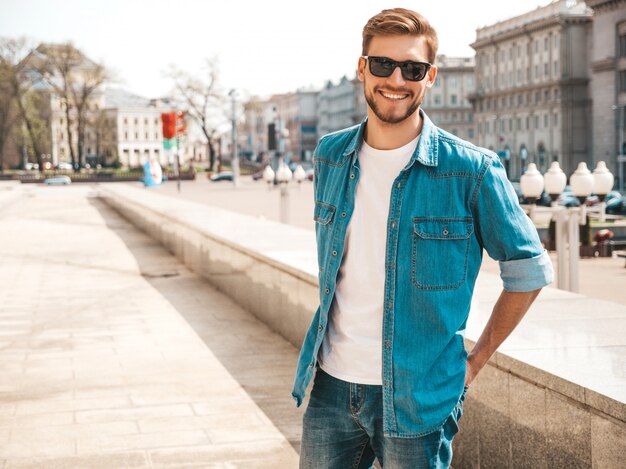 Retrato de guapo sonriente elegante hipster lumbersexual empresario modelo. Hombre vestido con ropa de chaqueta de jeans.