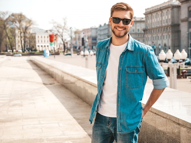 Retrato de guapo sonriente elegante hipster lumbersexual empresario modelo. Hombre vestido con ropa de chaqueta de jeans.