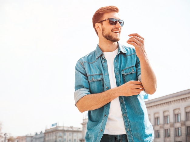 Retrato de guapo sonriente elegante hipster lumbersexual empresario modelo. Hombre vestido con ropa de chaqueta de jeans.