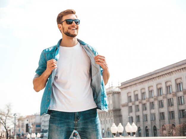 Retrato de guapo sonriente elegante hipster lumbersexual empresario modelo. Hombre vestido con ropa de chaqueta de jeans.