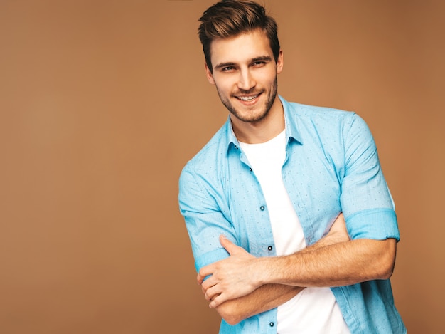 Retrato de guapo sonriente elegante joven modelo vestido con camisa azul ropa. Hombre de moda posando. Brazos cruzados