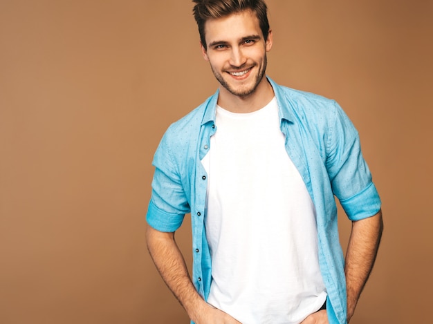 Foto gratuita retrato de guapo sonriente elegante joven modelo vestido con camisa azul ropa. hombre de moda posando