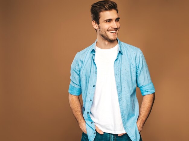 Retrato de guapo sonriente elegante joven modelo vestido con camisa azul ropa. Hombre de moda posando