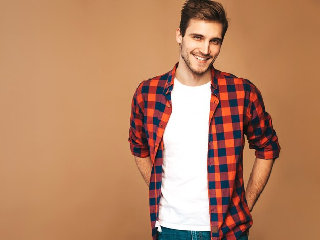 Retrato de guapo sonriente elegante joven modelo vestido con camisa a cuadros roja. Hombre de moda posando