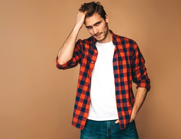 Retrato de guapo sonriente elegante joven modelo vestido con camisa a cuadros roja. Hombre de moda posando