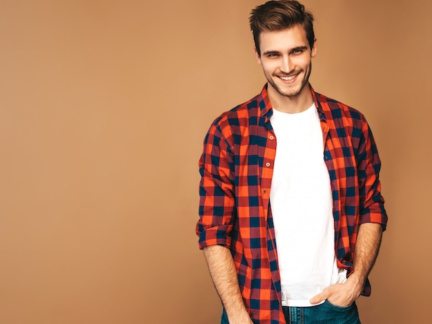 Retrato de guapo sonriente elegante joven modelo vestido con camisa a cuadros roja. Hombre de moda posando