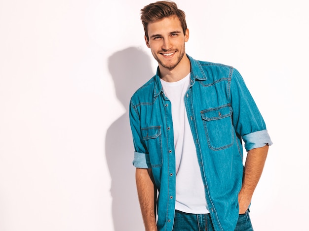 Retrato de guapo sonriente elegante joven modelo vestido con ropa de jeans. Hombre de moda