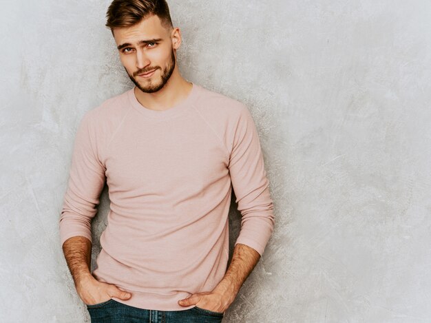 Retrato de guapo sonriente joven modelo vistiendo ropa casual verano rosa. Hombre elegante de moda posando