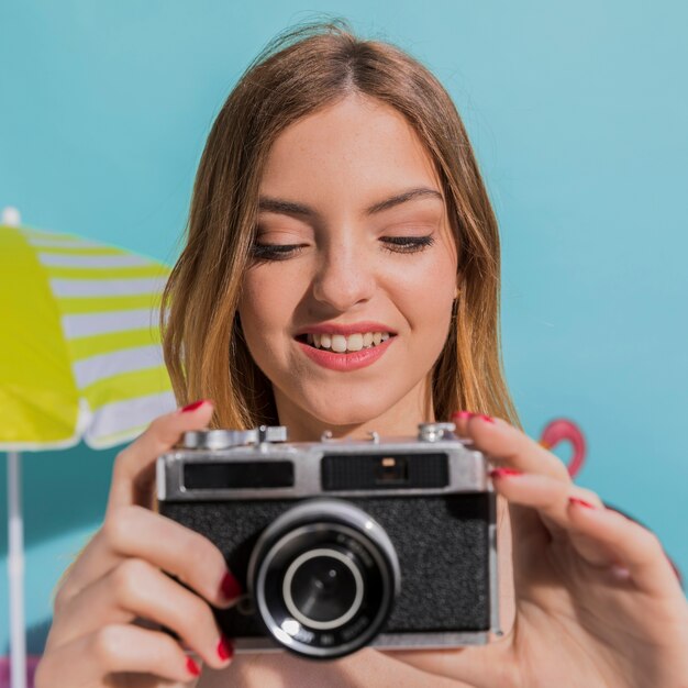 Retrato de la hembra joven sonriente que toma imágenes en cámara