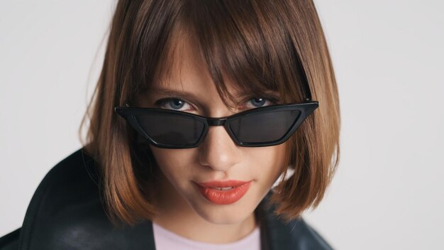 Retrato de una hermosa chica de ojos azules con cabello bob y labios rojos con gafas de sol aisladas de fondo blanco