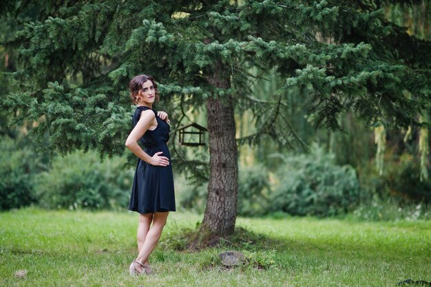 Retrato de una hermosa chica vestida de negro en una despedida de soltera posada en el parque