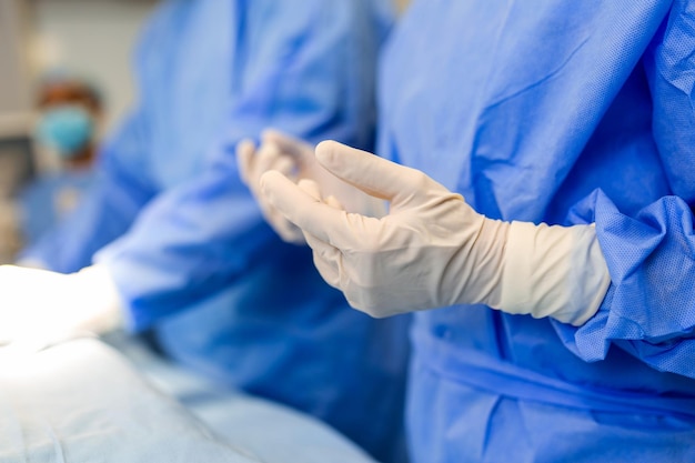 Retrato de una hermosa doctora cirujana poniéndose guantes médicos de pie en el quirófano Cirujano en el quirófano moderno