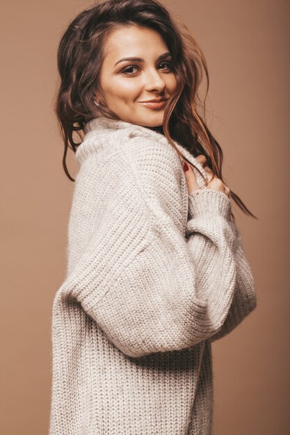 Retrato de hermosa dulce linda mujer morena sonriente. Chica casual suéter gris. Modelo posando en estudio
